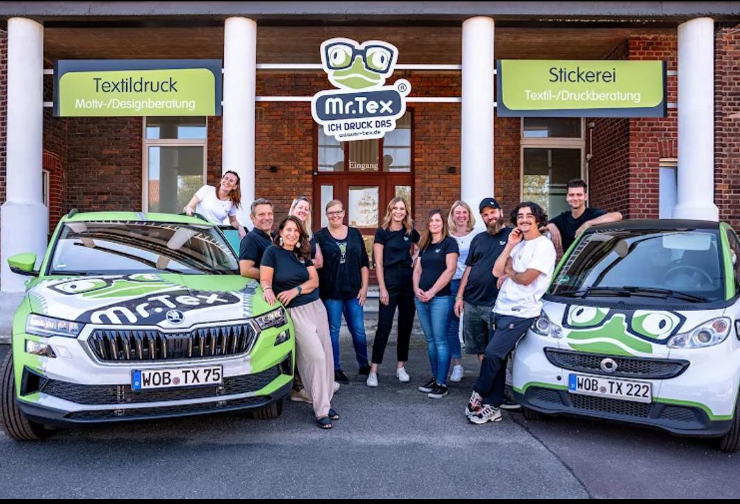 Das Team von Mr.Tex Wolfsburg vor dem Eingang mit den firmeneigenen Fahrzeugen
